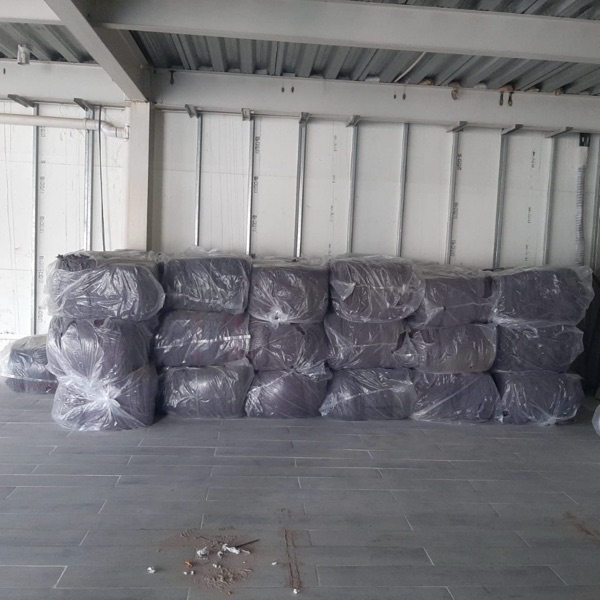 Bultos de cobijas apilados en bodega con embalaje transparente.