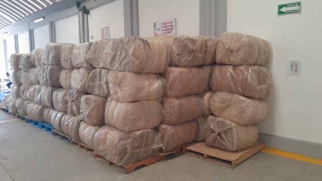 Inventario de pacas y bultos de cobijas estibadas sobre tarimas en bodega listas para mayoreo.