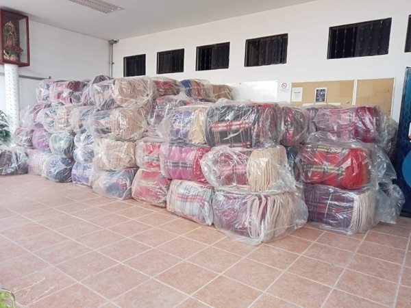 Estiba de paquetes de cobijas a cuadros y colores en almacén.